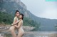 A couple of naked women standing next to each other near a river.