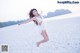 A woman in a white dress jumping in the air on a beach.