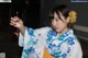 A woman in a blue and white kimono holding a flower in her hand.