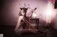 A woman sitting on the floor in a room with a lamp.