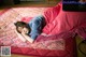 A young girl laying on a bed covered in a blanket.