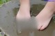 A person's feet in a puddle of water.