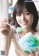 A woman holding a bowl of green and blue ice cream.