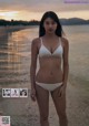 A woman in a white bikini standing on a beach.