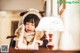 A little girl in a furry hat and scarf looking at a lamp.