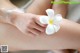 A woman holding a white flower on her arm.