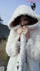 A woman wearing a white furry coat with a hood.