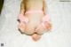 A baby wearing a pink thong and handcuffs on a bed.