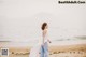 A woman walking on a beach near the ocean.