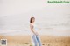 A woman standing on a beach next to the ocean.