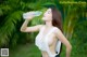 A woman drinking water from a bottle in a park.