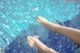 A woman's feet in a swimming pool with a pink flower floating in the water.