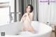 A naked woman sitting in a bathtub in a bathroom.