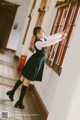 A woman in a school uniform leaning against a window.