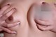 A close up of a woman's breasts with her hands on her breasts.