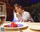 A woman sitting at a table with a plate of food and a glass of wine.